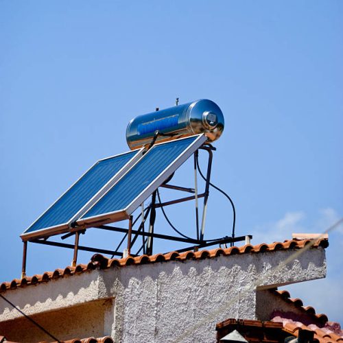 istockphoto-147661024-612×612 A solar water heater with solar panels on the roof of a house in Greece set against a clear blue sky.